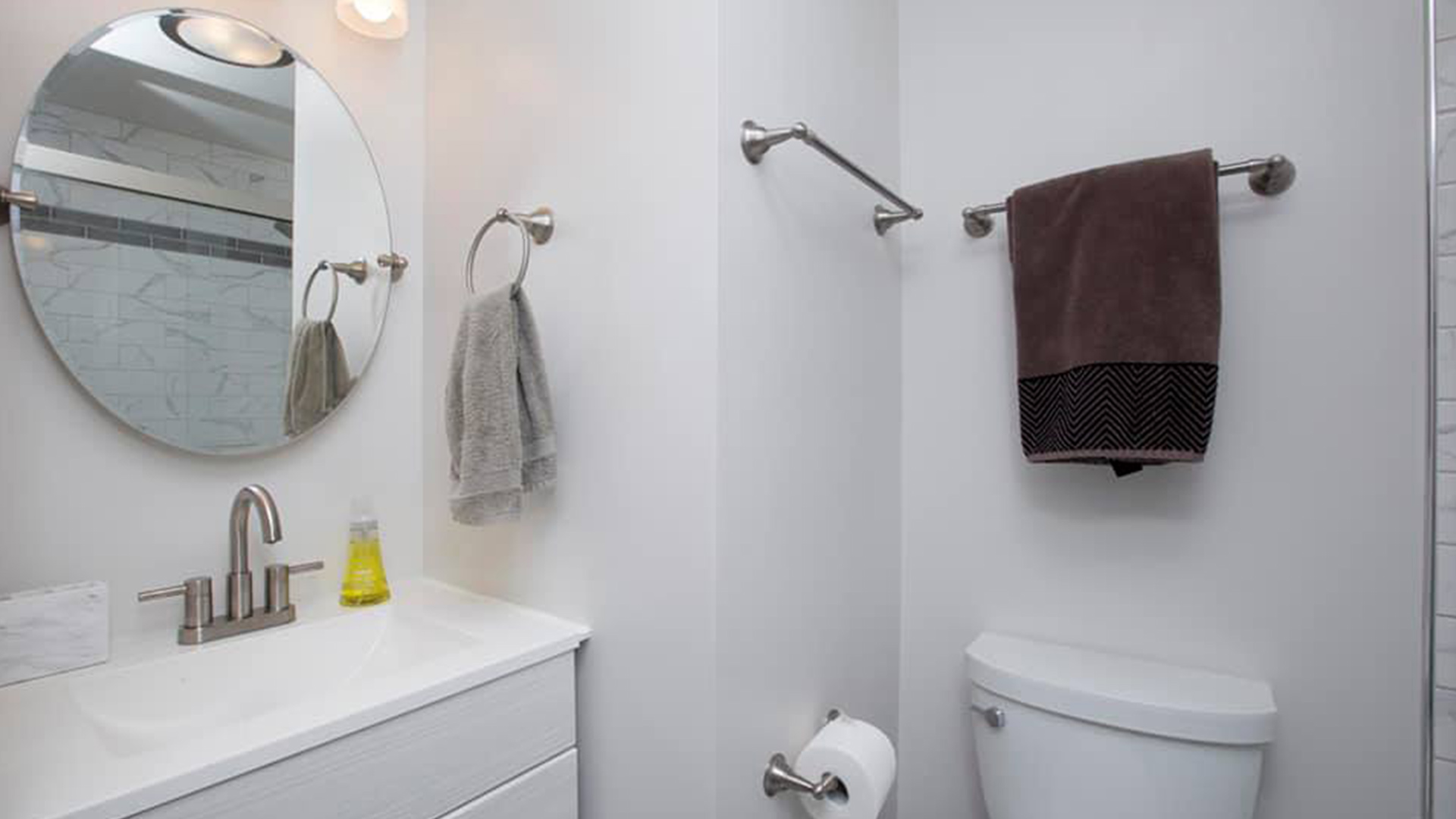 all-white-bathroom-with-circular-mirror-above-sink-goshen-in
